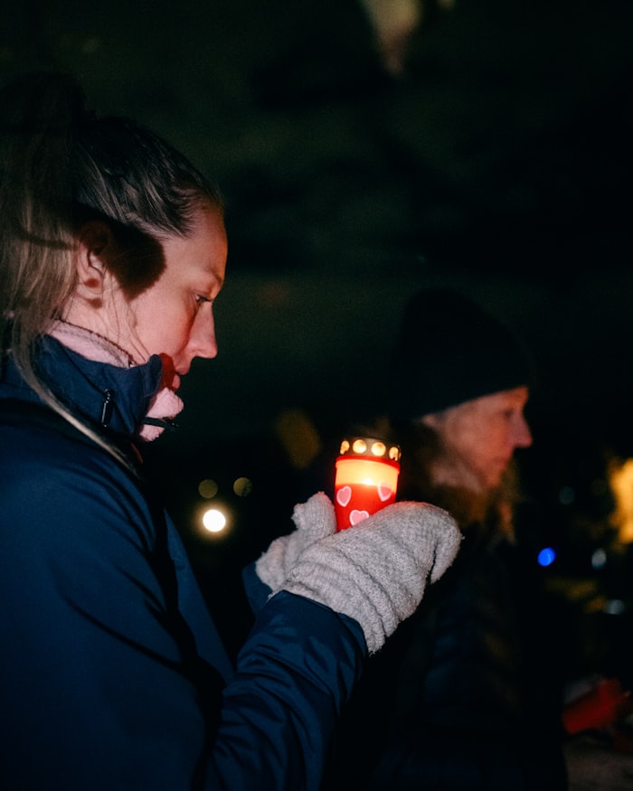 Woman holding a lit candle at night — representing grief and loss